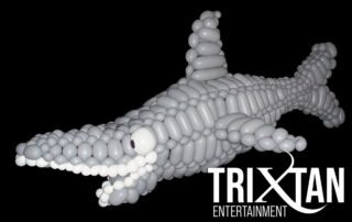 Realistic balloon sculpture of a gray shark with fins, tail, and open mouth on a black background